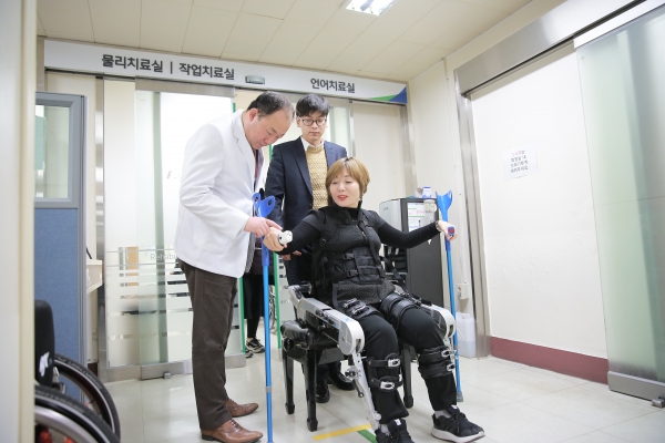 부산대병원 재활의학과 외래에서 장재혁 교수(재활의학과)가 하지 마비 장애환자 보행보조로봇 사용을 안내하고 있다. [사진=부산대병원]