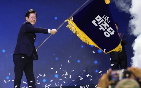 더불어민주당 당대표 연임에 성공한 이재명 신임 대표가 18일 서울 송파구 올림픽공원 KSPO돔에서 열린 전당대회에서 당기를 흔들고 있다. [사진=공동취재단, 연합뉴스]