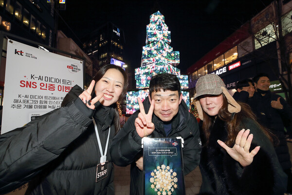 서울 신촌 거리에 설치된 KT ‘팬메이드 K-AI아이디어 챌린지’ 팝업 미디어 트리 앞에서 시민들이 기념 촬영을 하고 있다./사진=KT